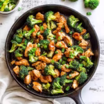 Paleo chicken and broccoli stir fry cooked in a skillet with fresh green scallions
